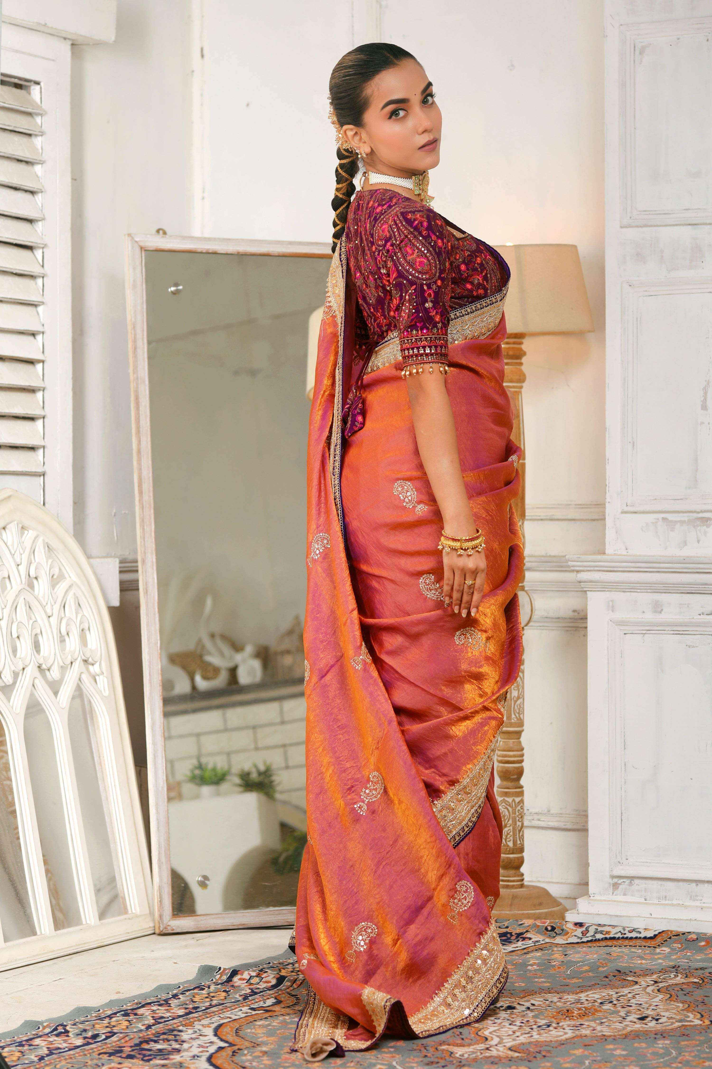 Model wearing a coral pink crushed saree with chahat-e-gehra blouse featuring elegant embroidery and embellishments.