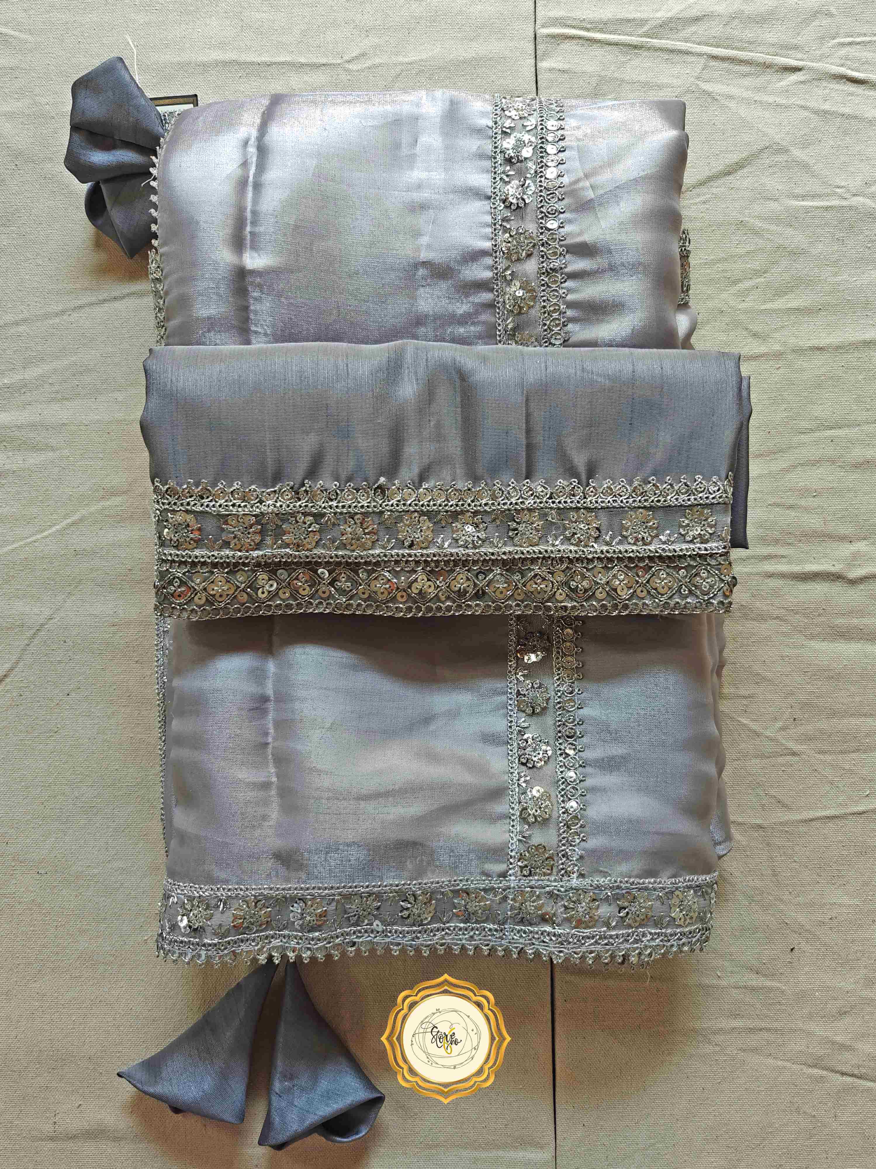 Silver organza saree with blouse featuring stunning lace work and cute tassels, perfect for elegant occasions.