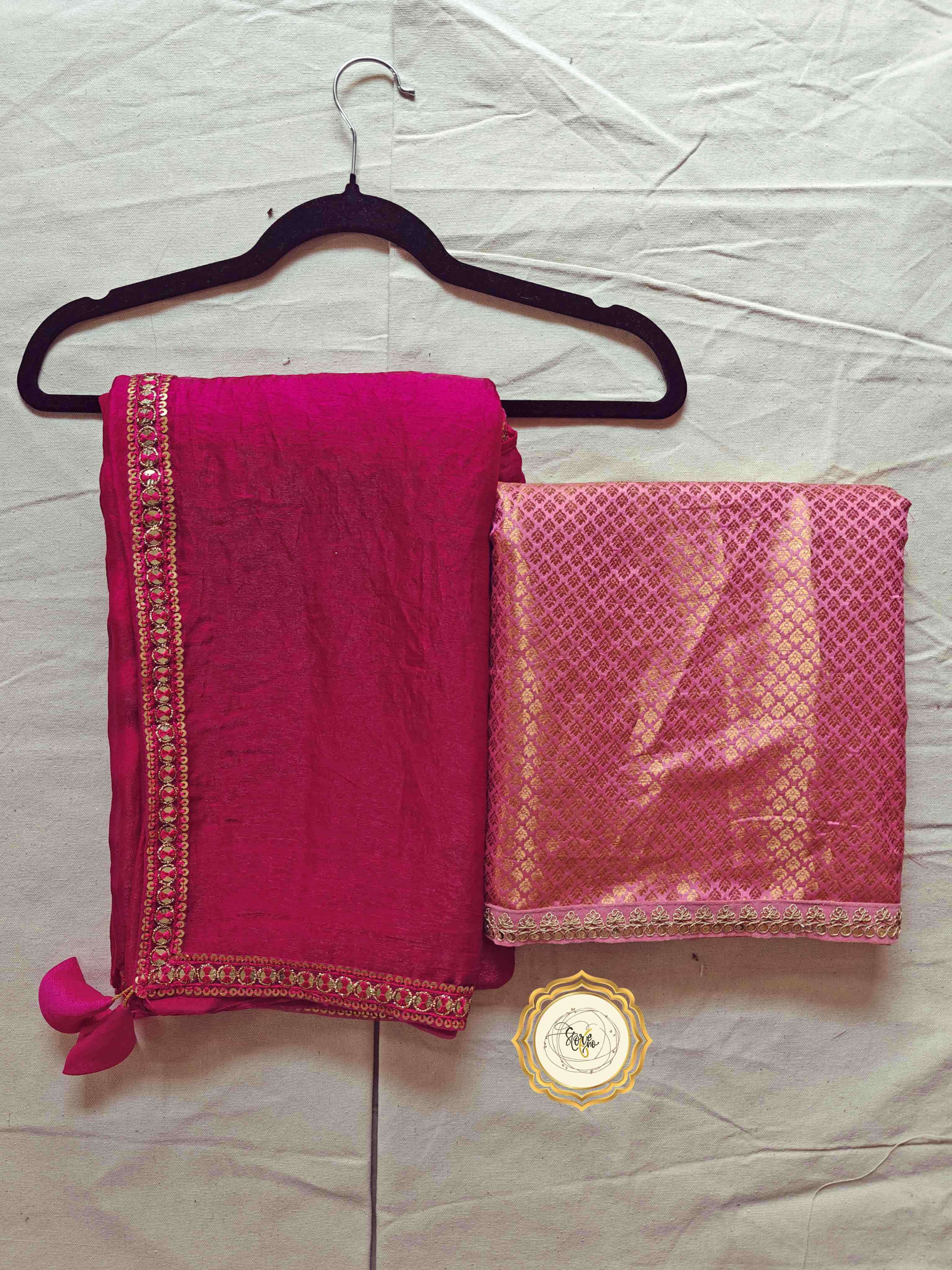 premium pink saree with unstitched blouse displayed on a hanger, featuring intricate lace work and lovely tassels.