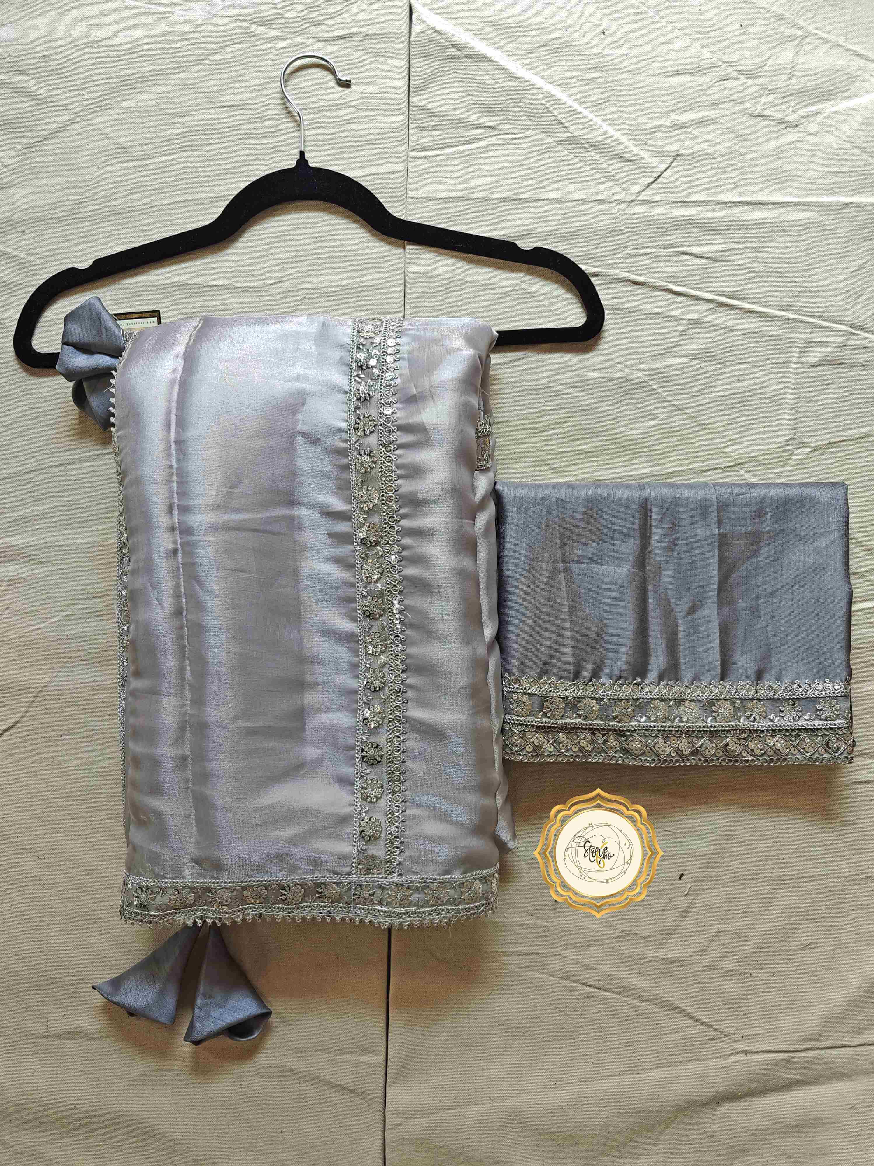 Silver organza saree with blouse showcasing elegant lace work and cute tassels.