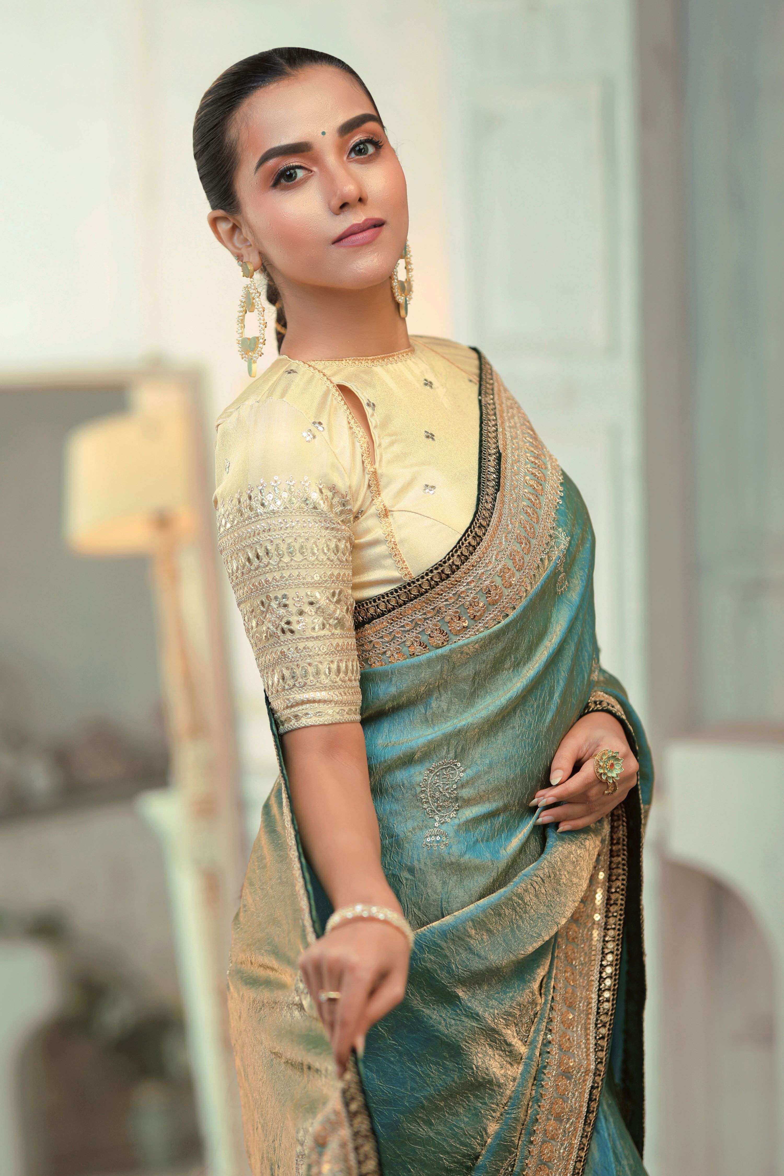 Teal blue saree with champagne blouse featuring embroidered borders and elegant styling.