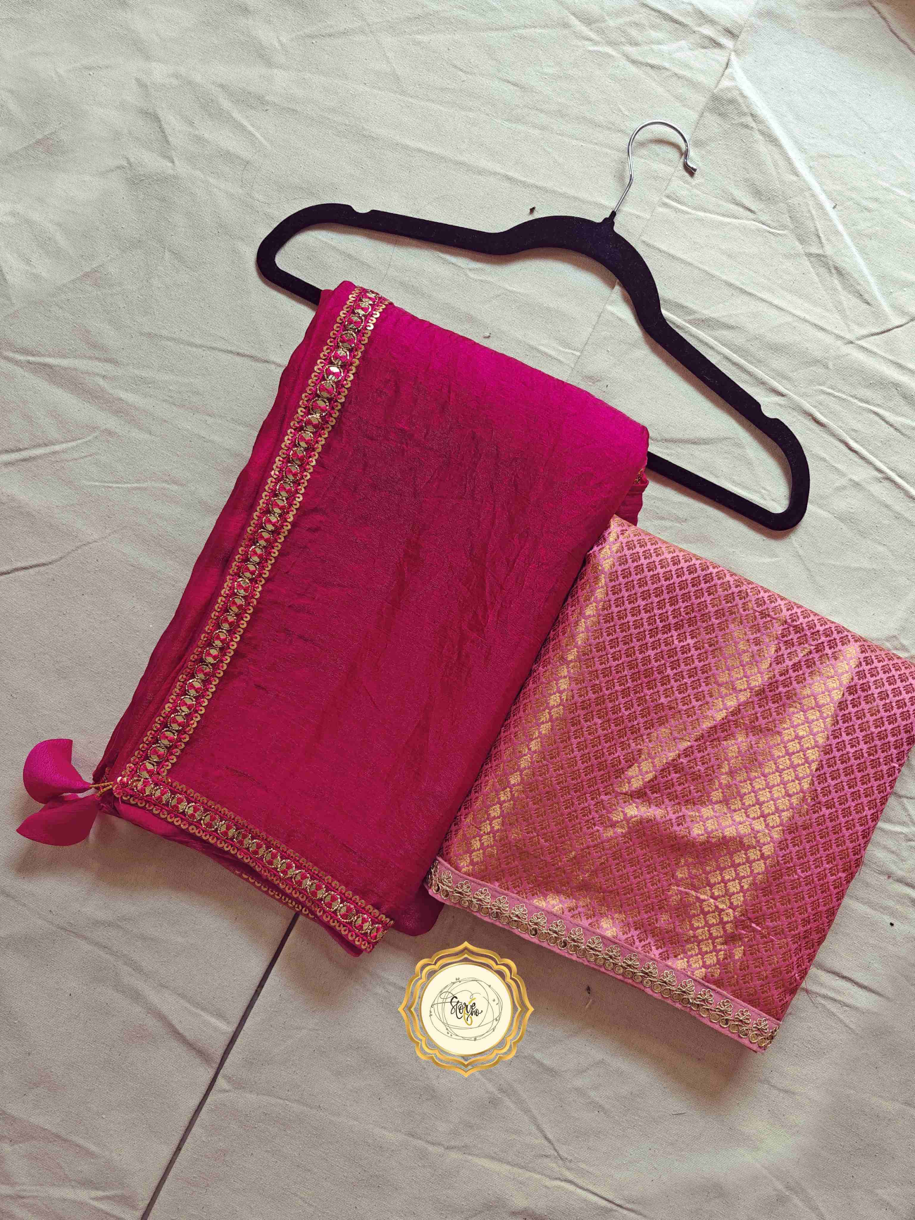 premium pink saree with unstitched blouse displayed on a hanger, featuring intricate lace work and lovely tassels.